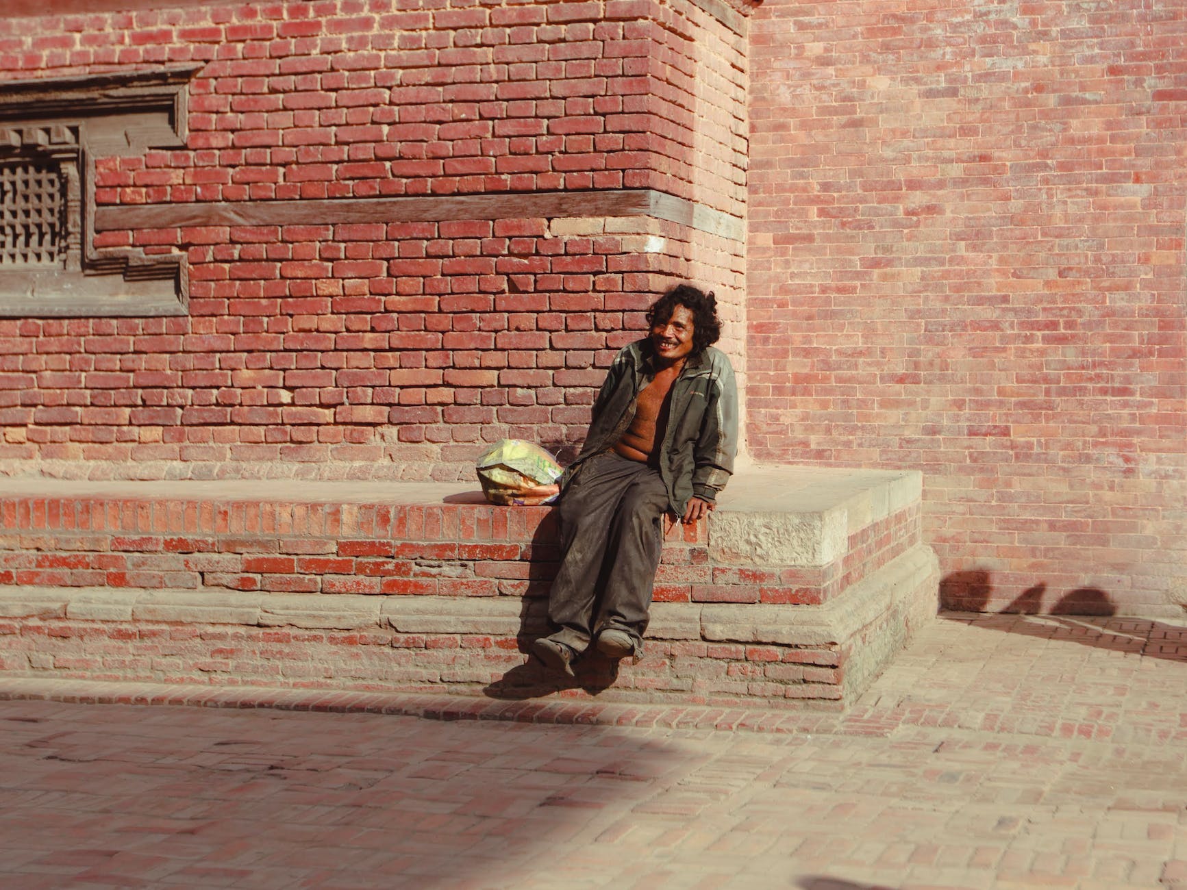 homeless man sitting near brick building.  Did he discover his antichrist?