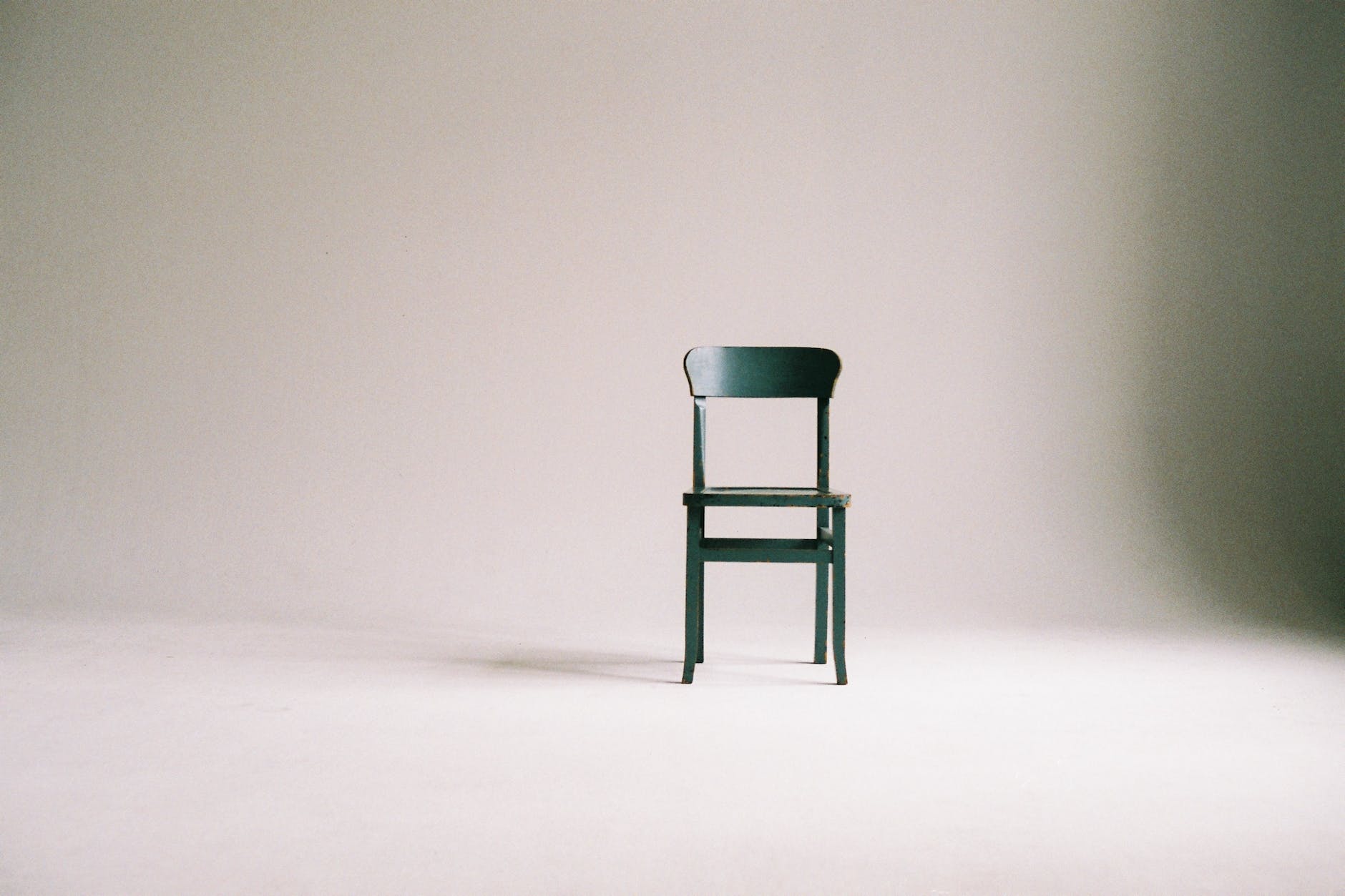 empty wooden chair on a white wall studio illustrating the know thyself religion