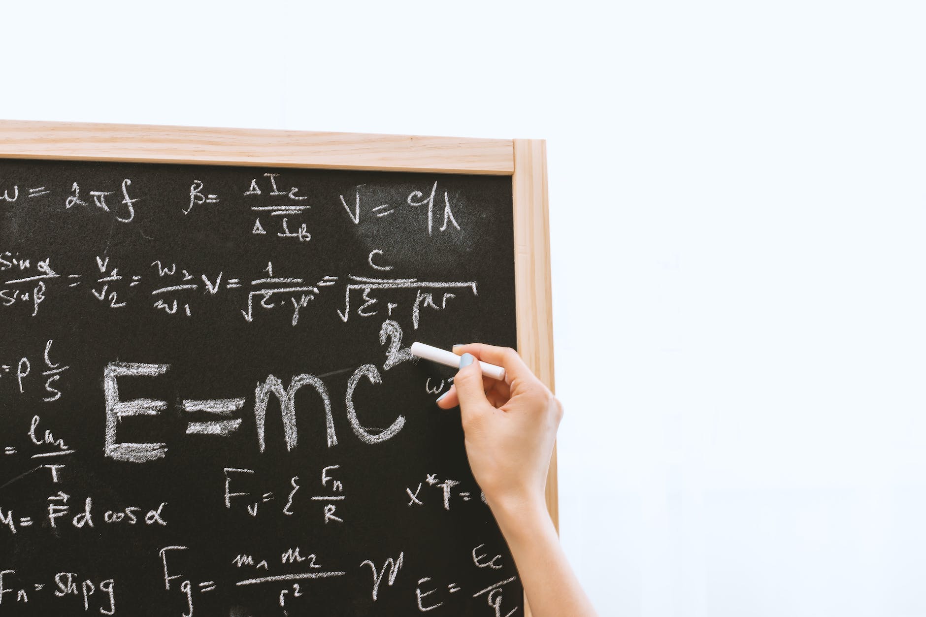 person holding a chalk in front of the chalk board. Einstein's theory replaced Newton's theory to stop us from being wrong.